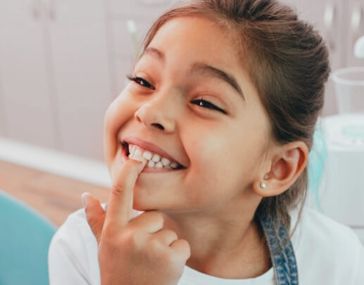 Child pointing to smile after dental sealant treatment