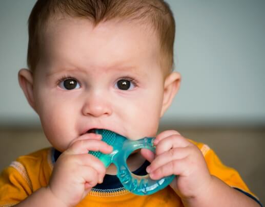 Teething baby chewing on a toy