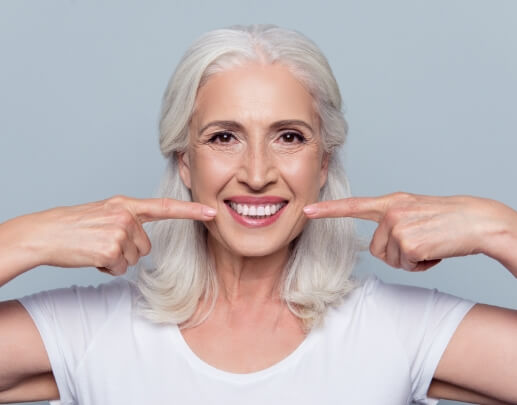 Dental patient pointing to smile after gum recontouring treatment