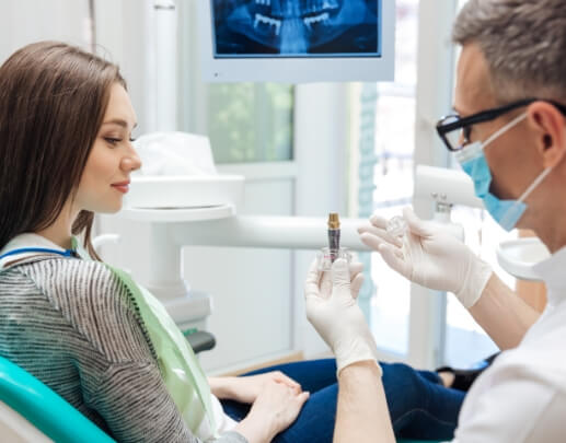 Dentist showing dental implant model to dental patient