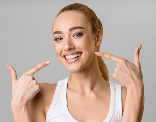 Woman pointing to flawless smile after porcelain veneers